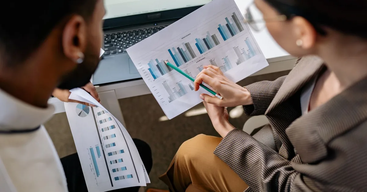 Two colleagues reviewing website performance charts beside a laptop