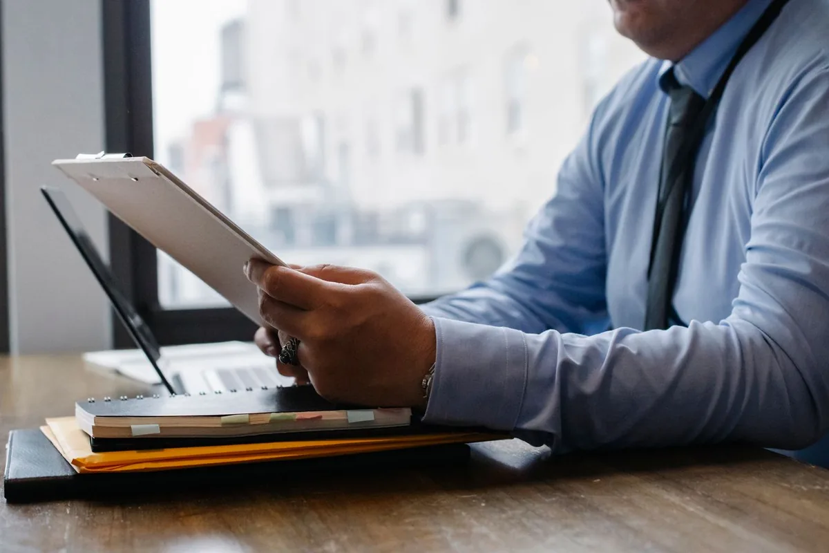 Reviewing a checklist on a clipboard beside a laptop before updates